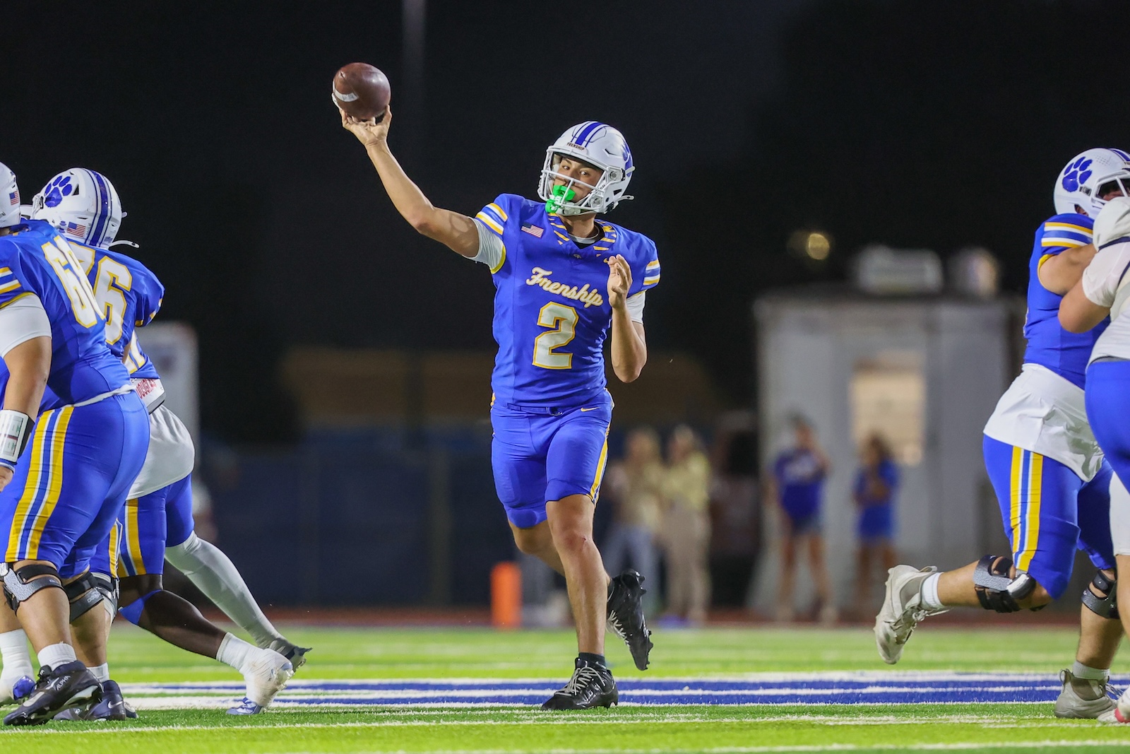 Seabolt Chase-18540 | Press Pass Sports A football quarterback in blue and yellow uniform throws a pass during a nighttime game.
