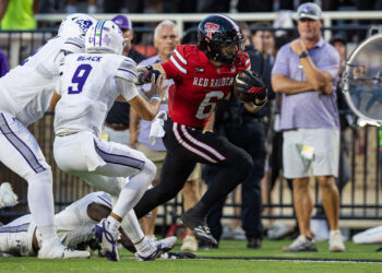 Tech-Abilene-FB-19 | Press Pass Sports American football player in red jersey (No. 6) runs with the ball as white-clad defenders close in on the field goal line.
