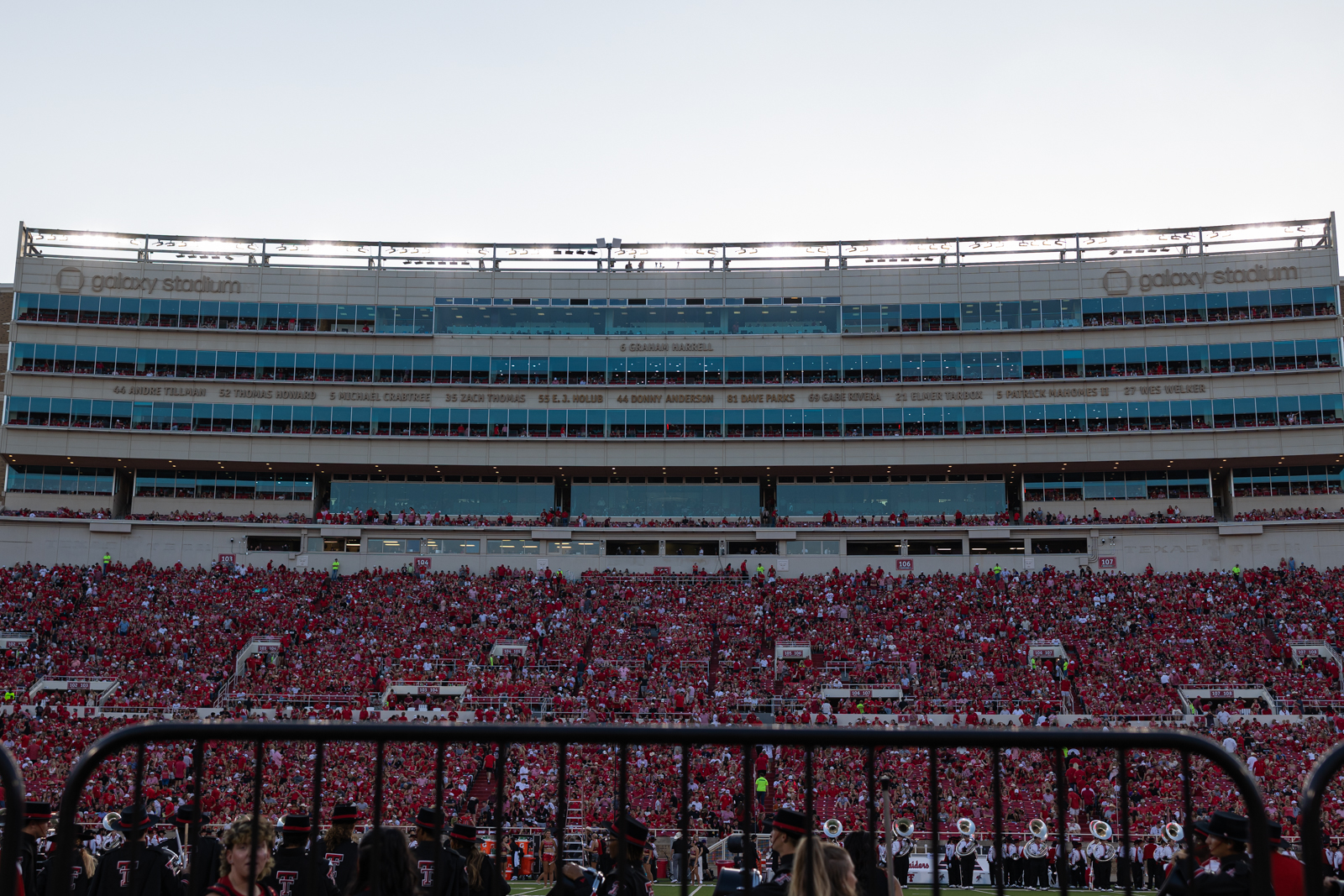 Tech-Abilene-FB-17 | Press Pass Sports Wide view of a football stadium packed with red-clad fans, with a marching band performing on the field in the foreground.