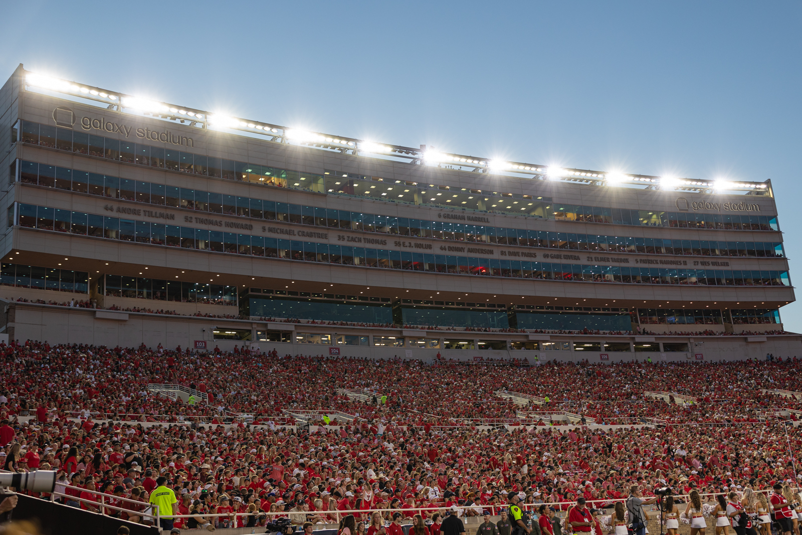 Tech-Abilene-FB-22 | Press Pass Sports A large football stadium filled with red-clad spectators across the stands, with bright lights atop a multi‑level press box labeled'galaxy stadium'.