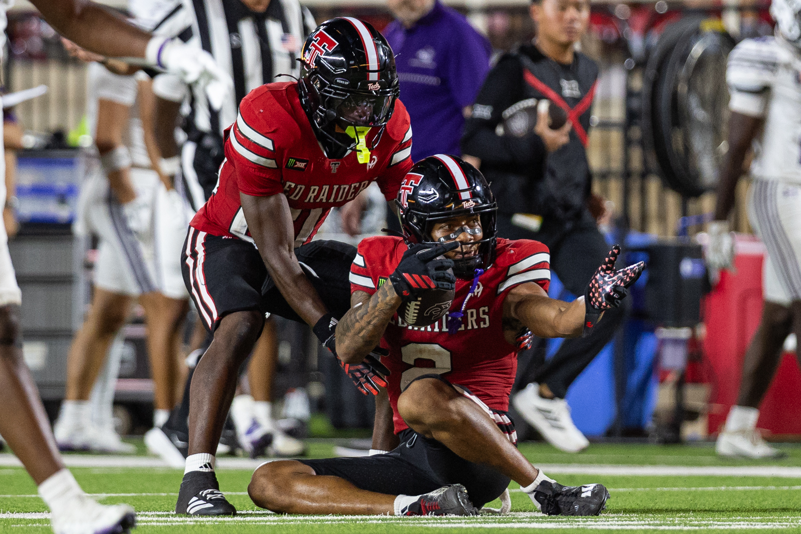 Tech-Abilene-FB-24 | Press Pass Sports Two football players in red and black uniforms collide on the field, one tackling the other as they reach for the ball.