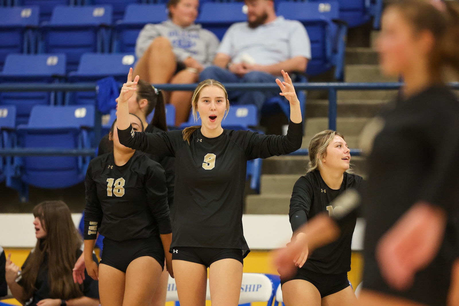 Seabolt Chase-12597 | Press Pass Sports Girls' volleyball team celebrating on the court, player wearing number 9 raises arms in triumph with teammates nearby.