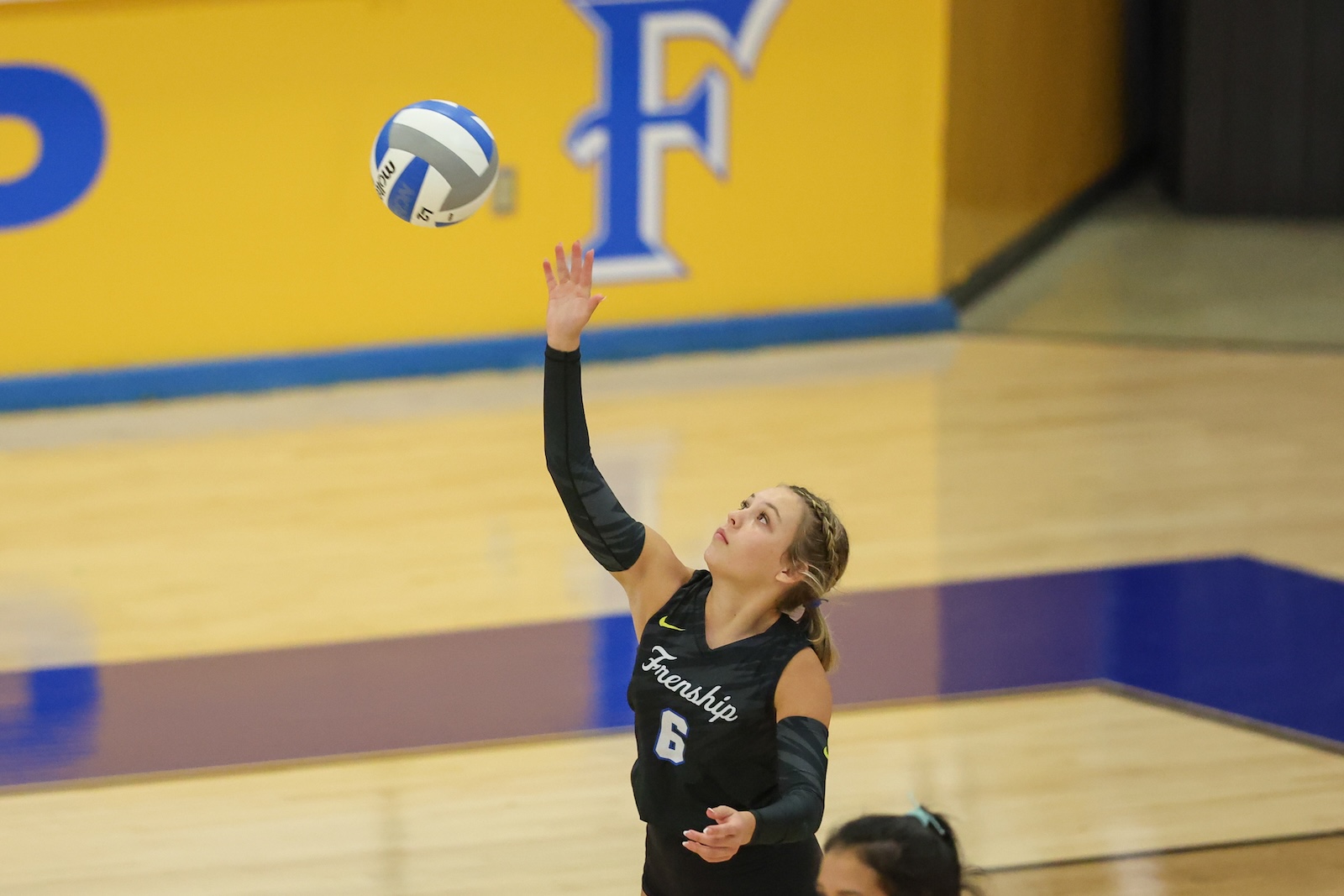 Seabolt Chase-13122 | Press Pass Sports Female volleyball player in a black jersey #6 serving the ball on an indoor court.
