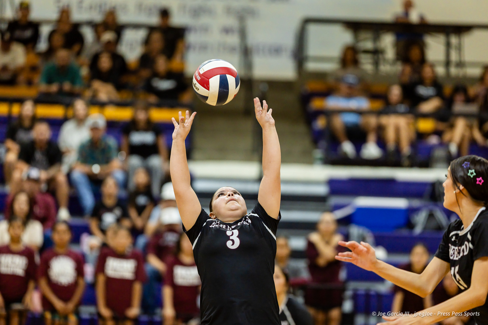 herford-vs-canyon-volleyball-jpegJoe-pps-17 | Press Pass Sports Female volleyball player in black jersey #3 jumps to set the ball as spectators watch from the bleachers at a crowded gymnasium.