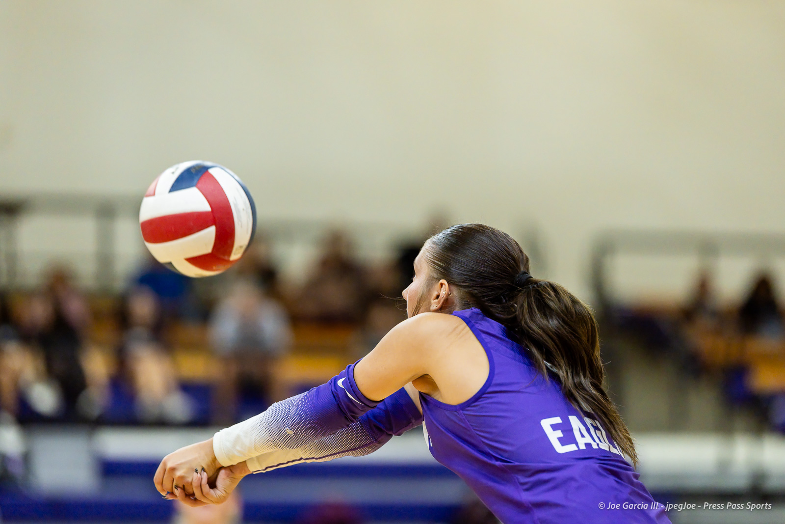 herford-vs-canyon-volleyball-jpegJoe-pps-21 | Press Pass Sports Woman volleyball player in purple jersey reaching to bump a white, red, and blue ball in an indoor gym.