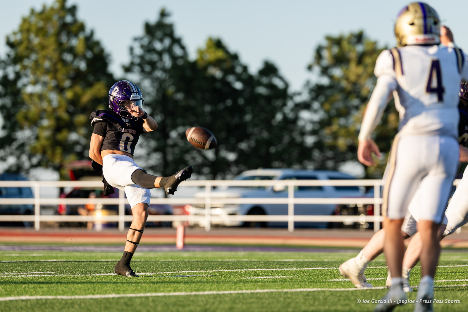 dalhart-vs-panhandle-football-jpegJoe-pps-9 | Press Pass Sports Football kicker in a black jersey (#8) boots the ball during a sunny game, with white-uniformed players nearby.