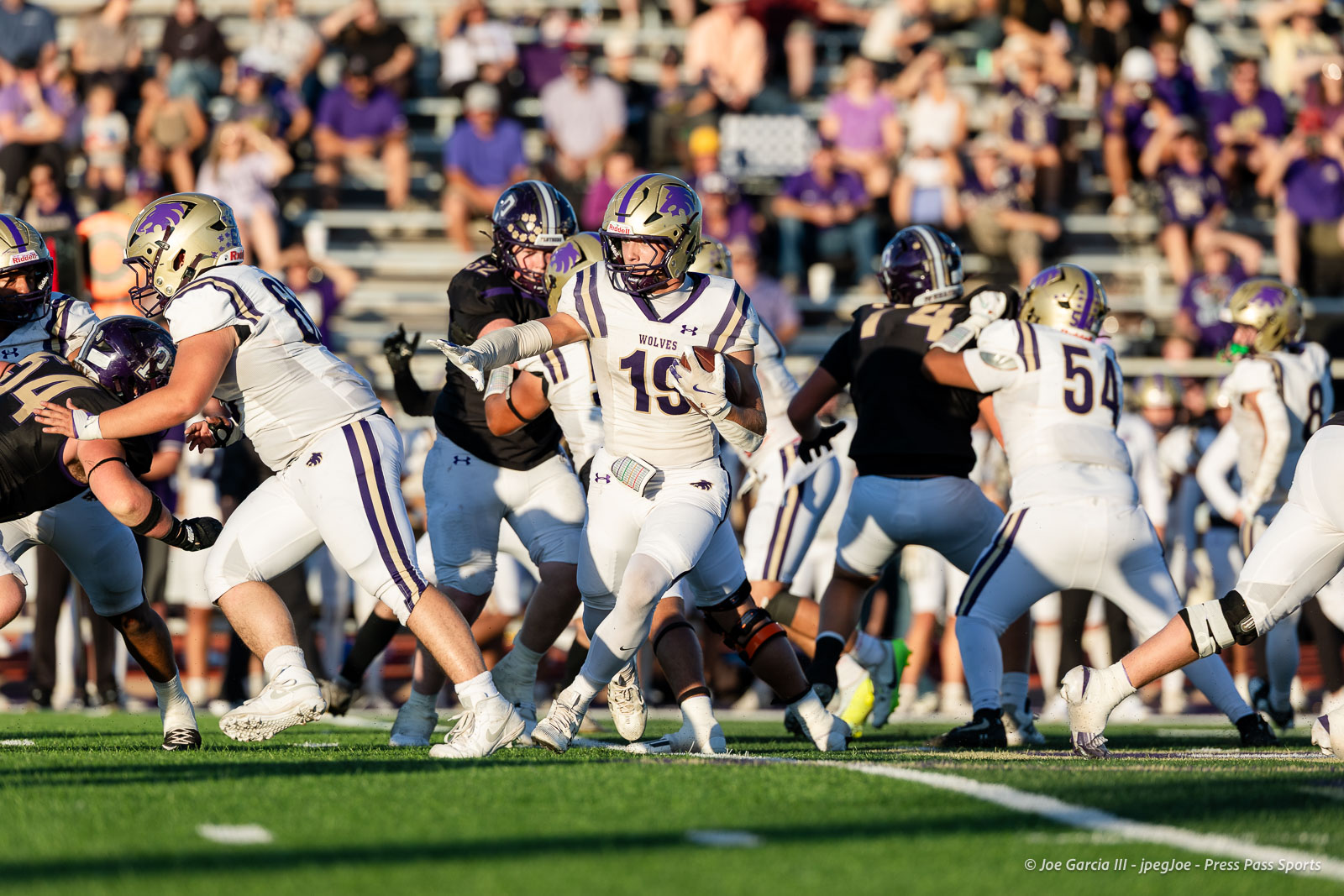 dalhart-vs-panhandle-football-jpegJoe-pps-11 | Press Pass Sports Quarterback (#19) hands off or passes the ball during a Wolves football game with offensive linemen and defenders in action on the field.
