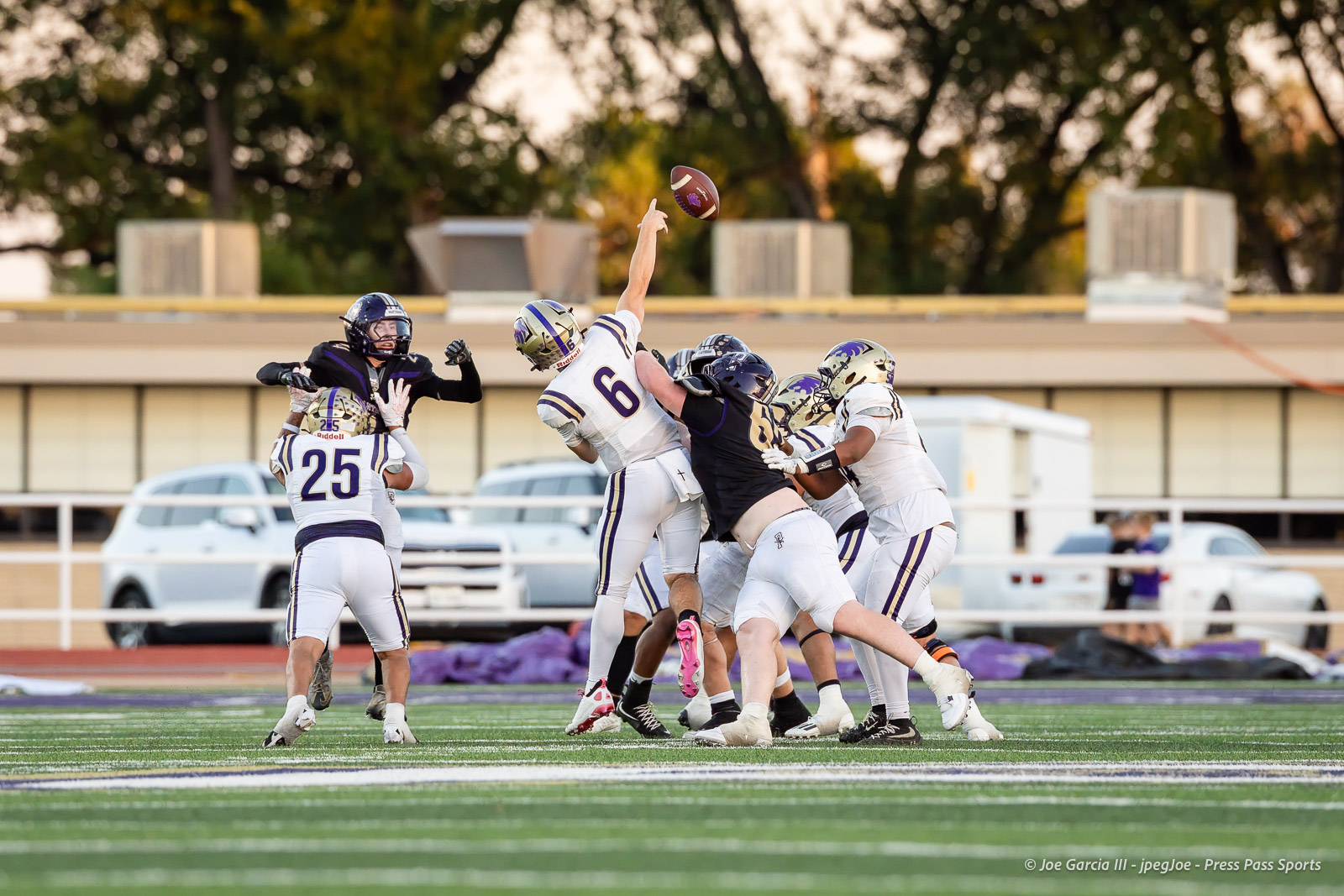 dalhart-vs-panhandle-football-jpegJoe-pps-20 | Press Pass Sports Players in white and purple leap for a loose football mid-air during a tense line-of-scrimmage moment on a green turf field.