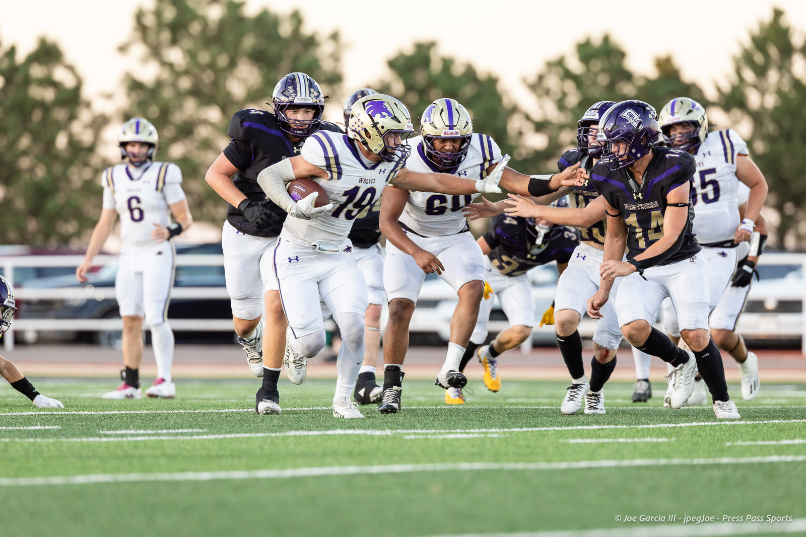 dalhart-vs-panhandle-football-jpegJoe-pps-22 | Press Pass Sports American football game in progress: running back with the ball pushes forward while teammates block and defenders reach in, on a green turf field.