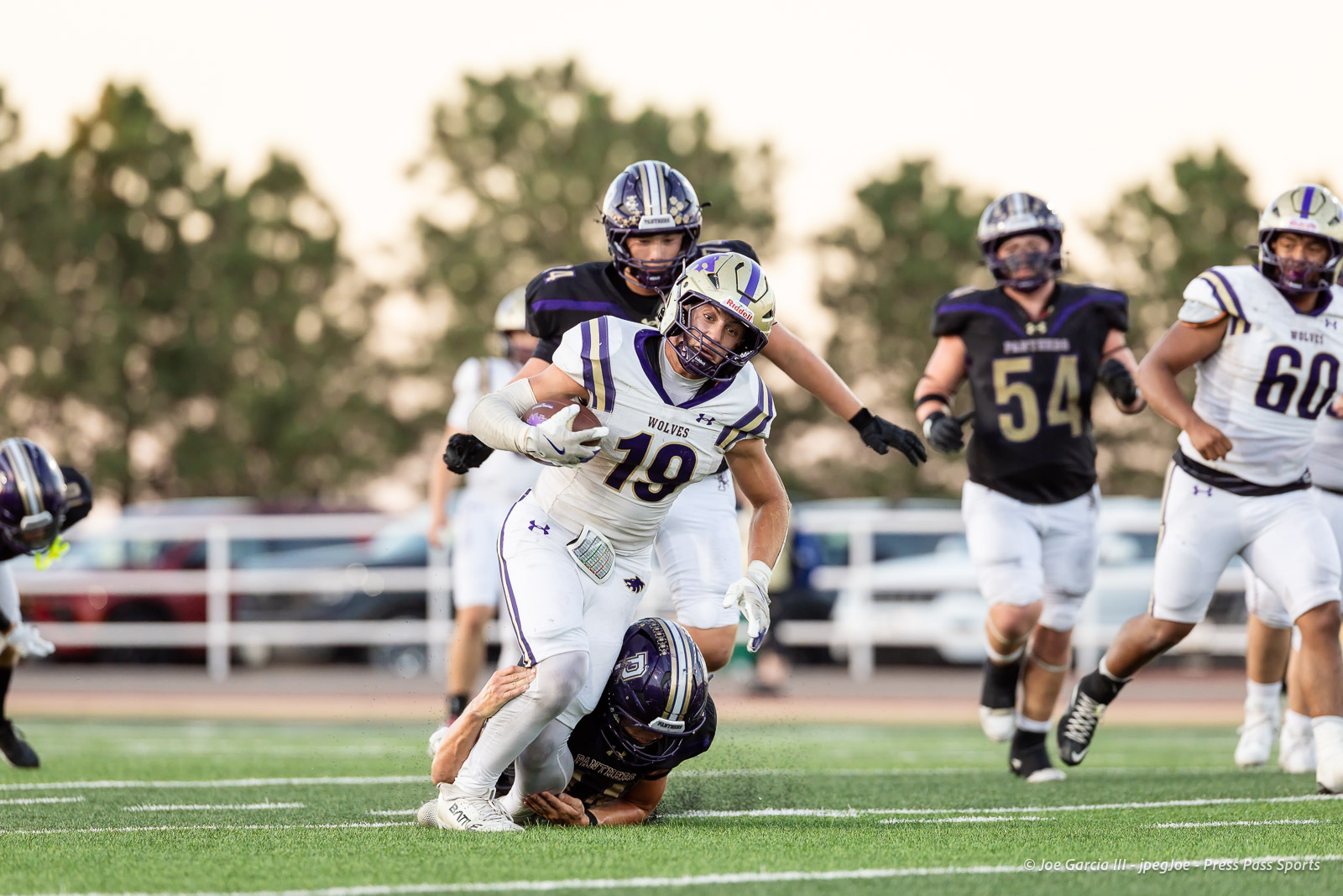 dalhart-vs-panhandle-football-jpegJoe-pps-23 | Press Pass Sports American football player wearing white Wolves jersey #19 runs with the ball as a defender in black closes in on a tackle on the grassy field.