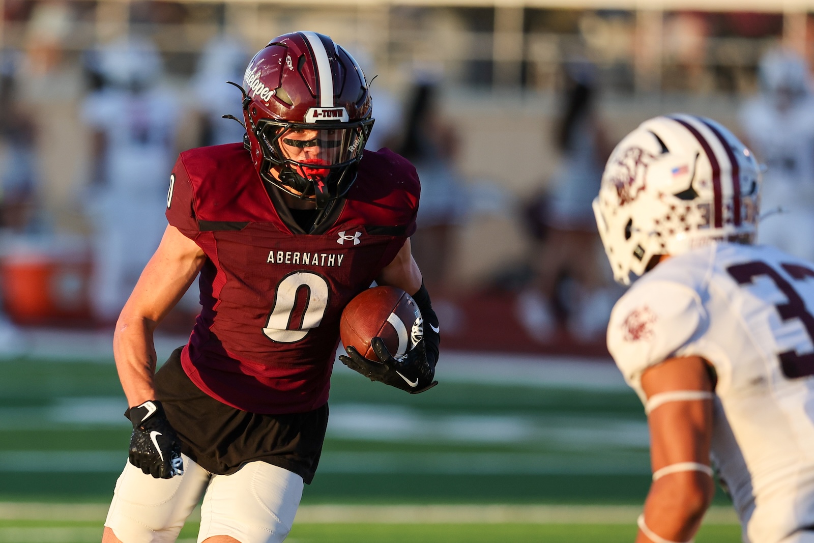 Abernathy football player (No. 0) runs with the ball during a game, facing a defender in white.