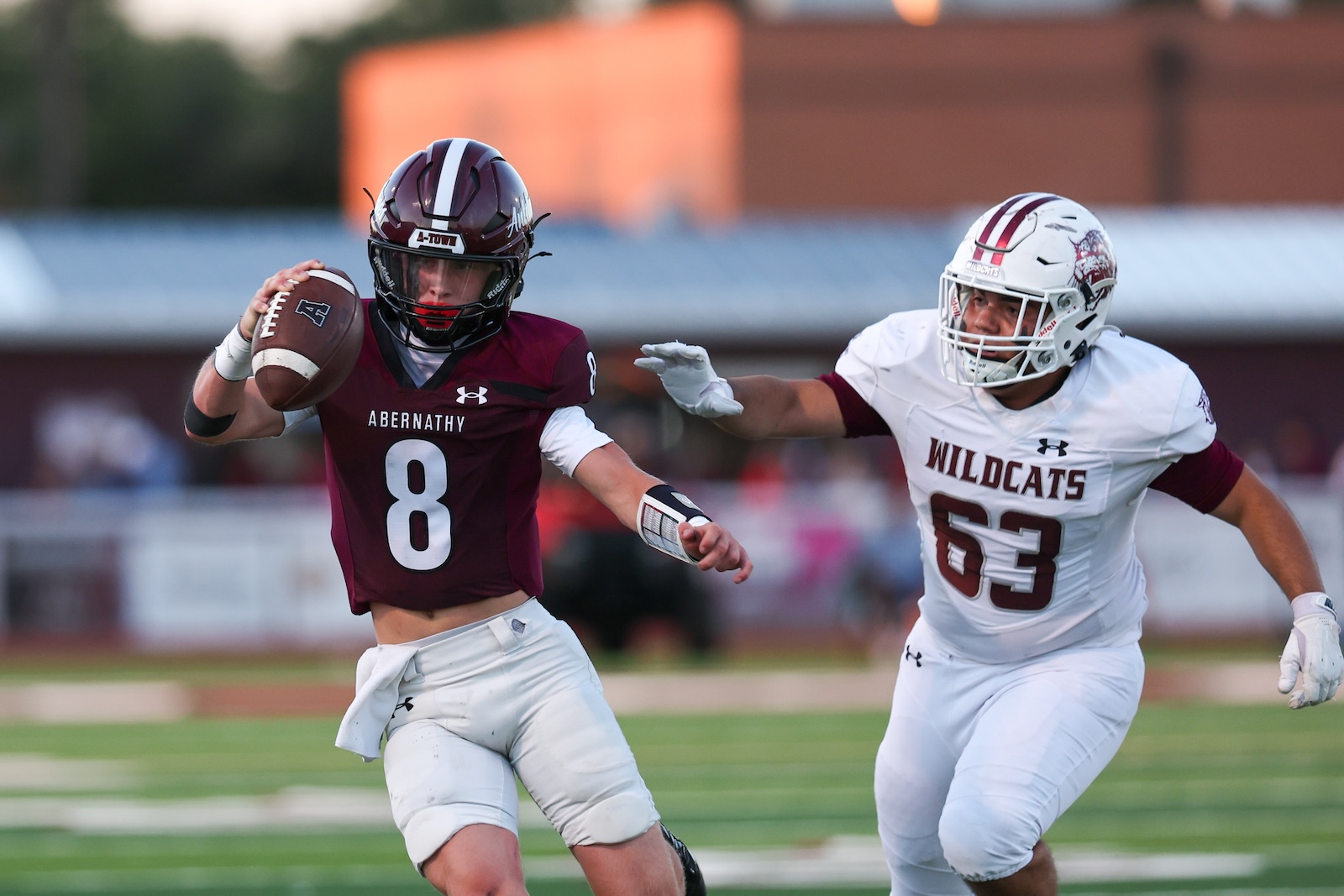 Maroon Abernathy quarterback #8 runs with the ball as a Wildcats defender pursues in white #63.