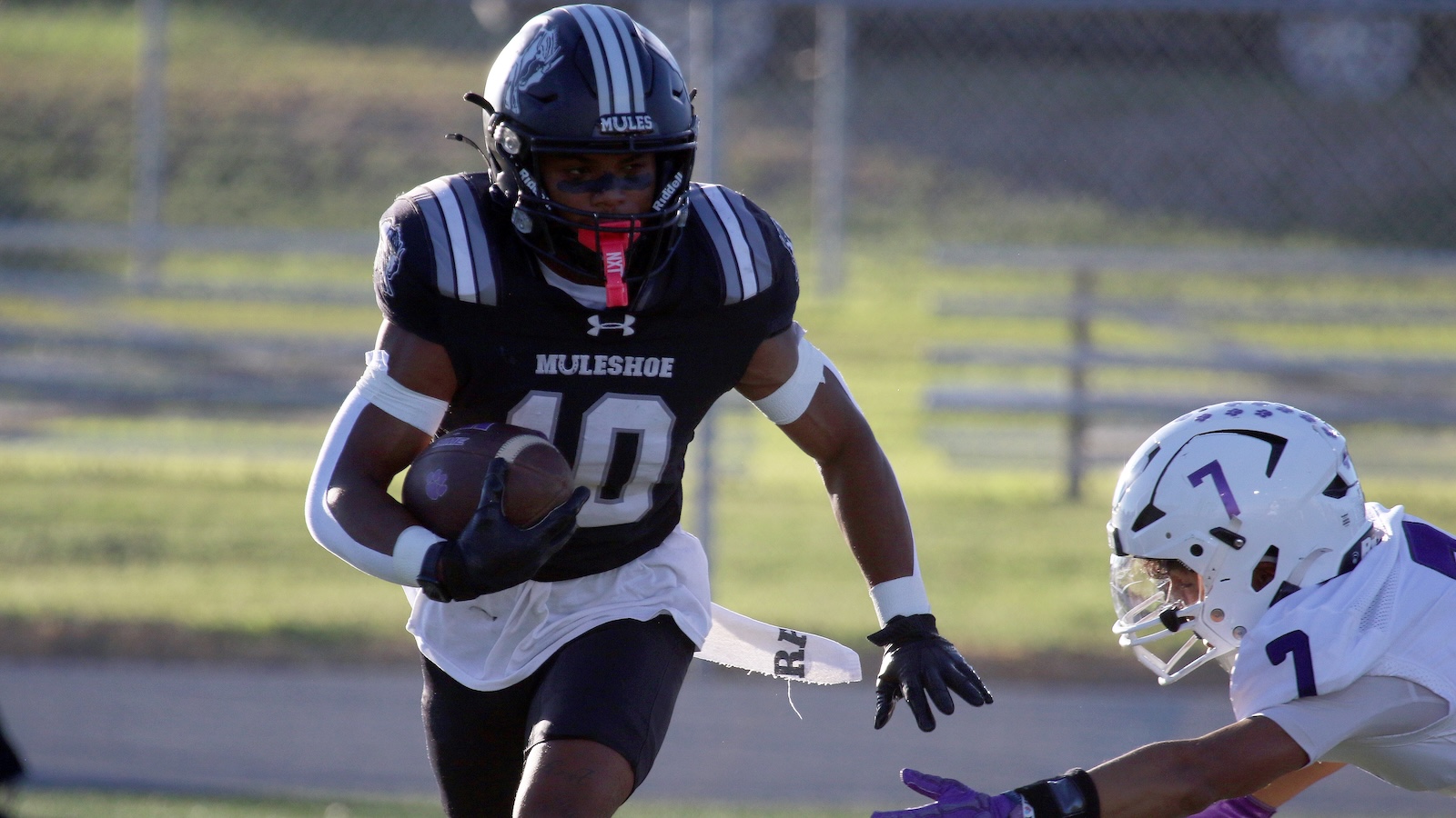Football player in a black Muleshoe jersey (#40) runs with the ball, pursued by a white-uniform defender nearby.