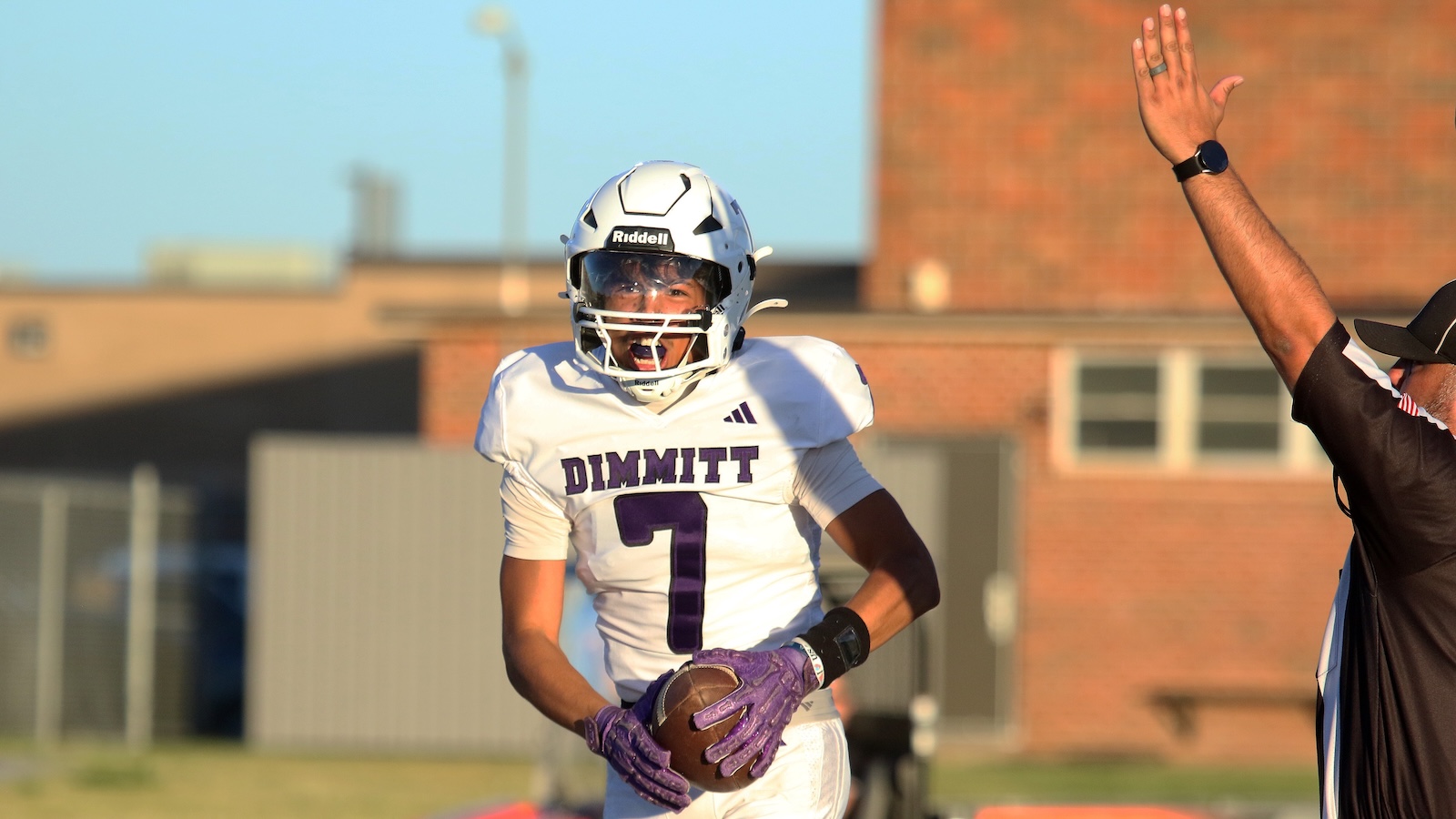Football player in white DIMMITT jersey #7 runs with the ball, celebrating a touchdown on the field.