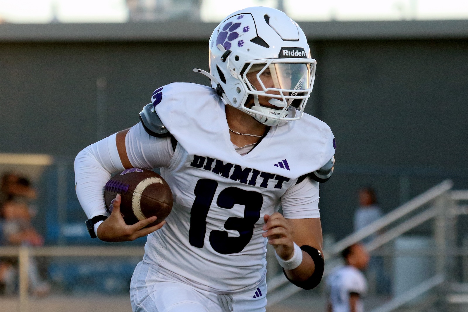 Dimmit football player in a white jersey, number 13, running with the ball during a game.