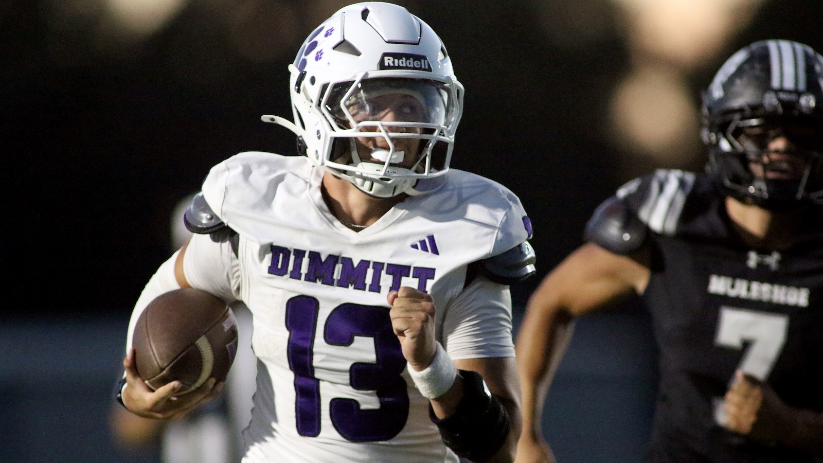 Football player in a white Dimmitt jersey (#13) runs with the ball during a game, looking ahead for a path to the end zone.