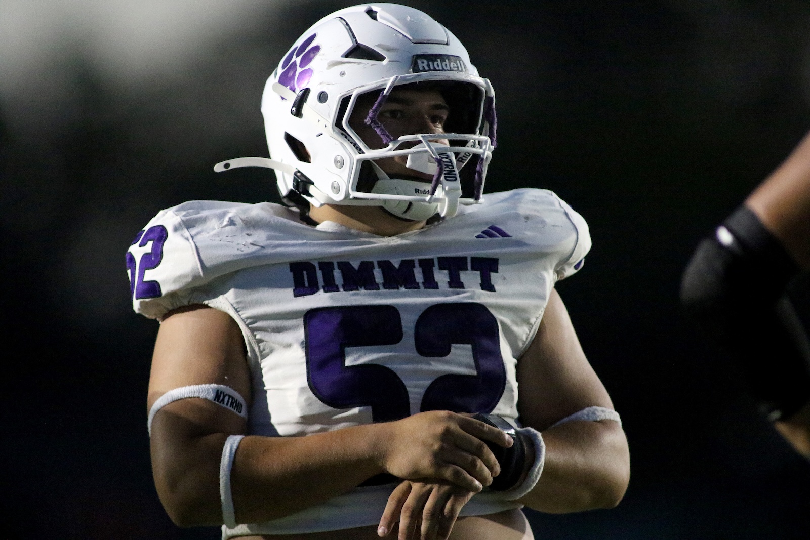 Football player in a white DIMMITT jersey with number 52 and purple trim, wearing a white helmet with a purple paw decal, on the field.