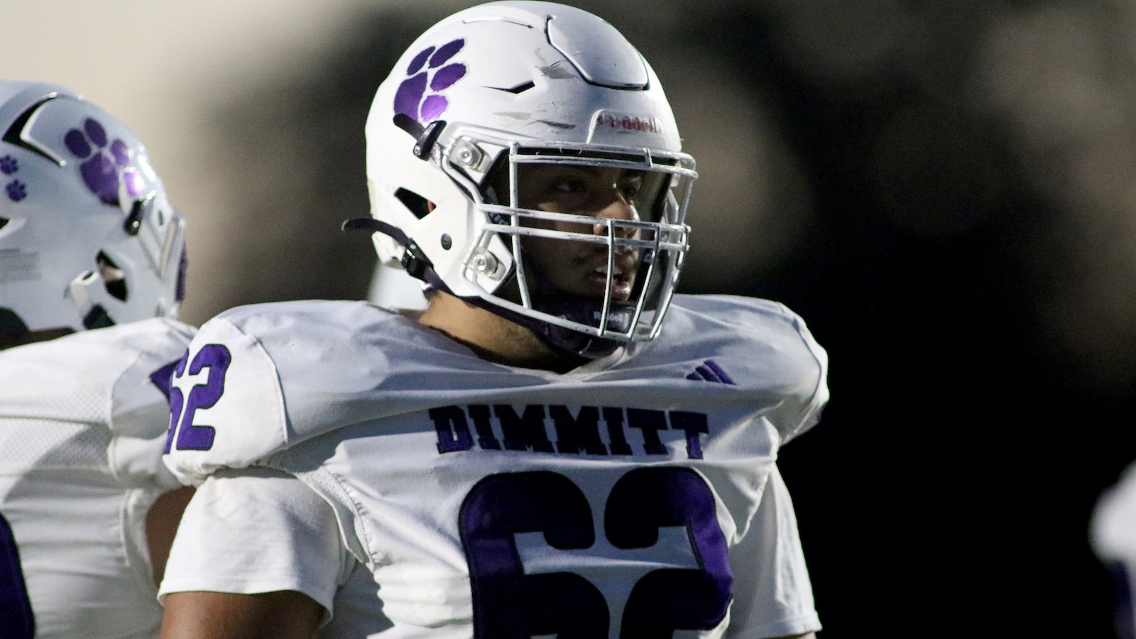 Football player in a white and purple uniform with number 32, wearing a helmet on the field for DIMMIT.