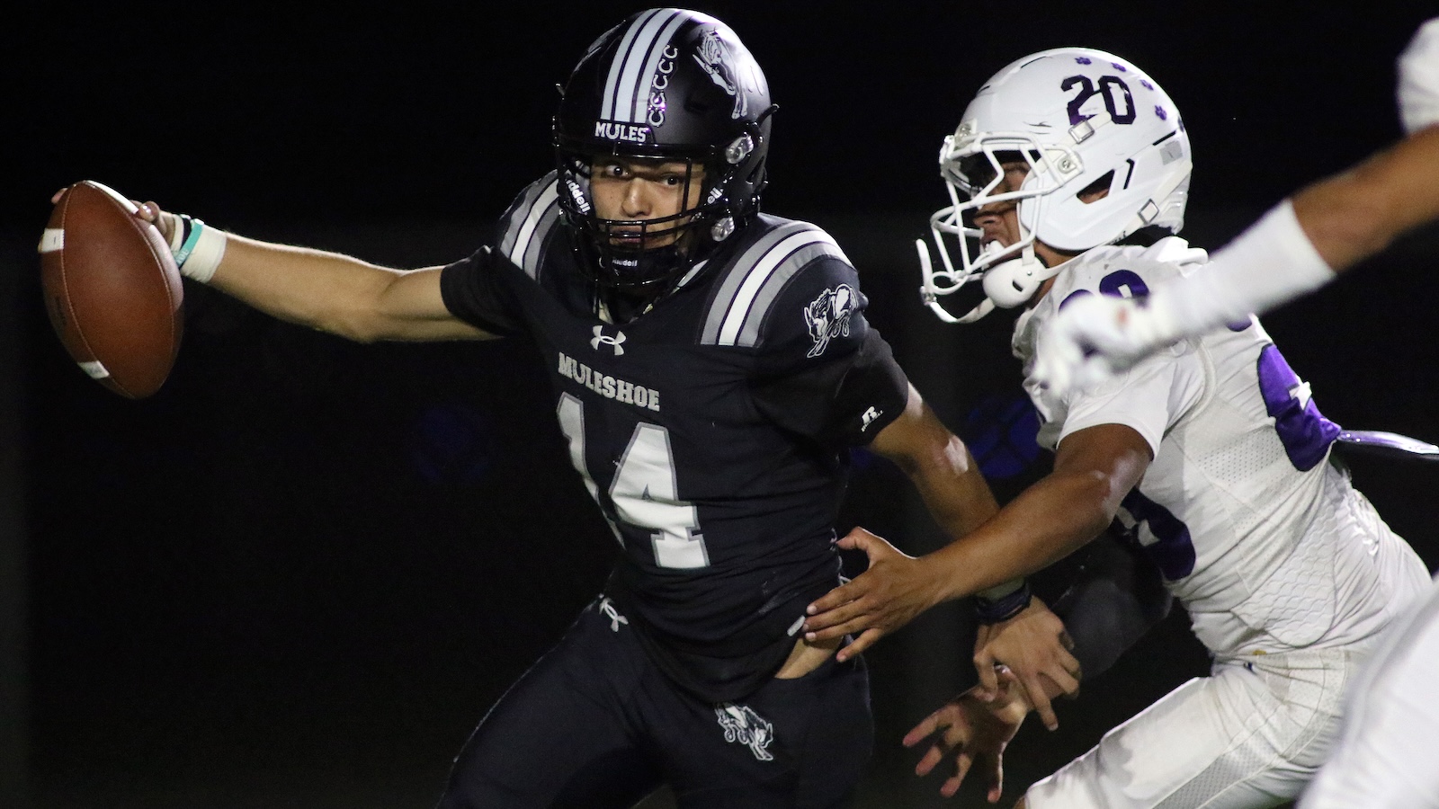 Muleshoe player wearing #14 in a dark uniform runs with the football, dodging a tackler in a white jersey during a night game.