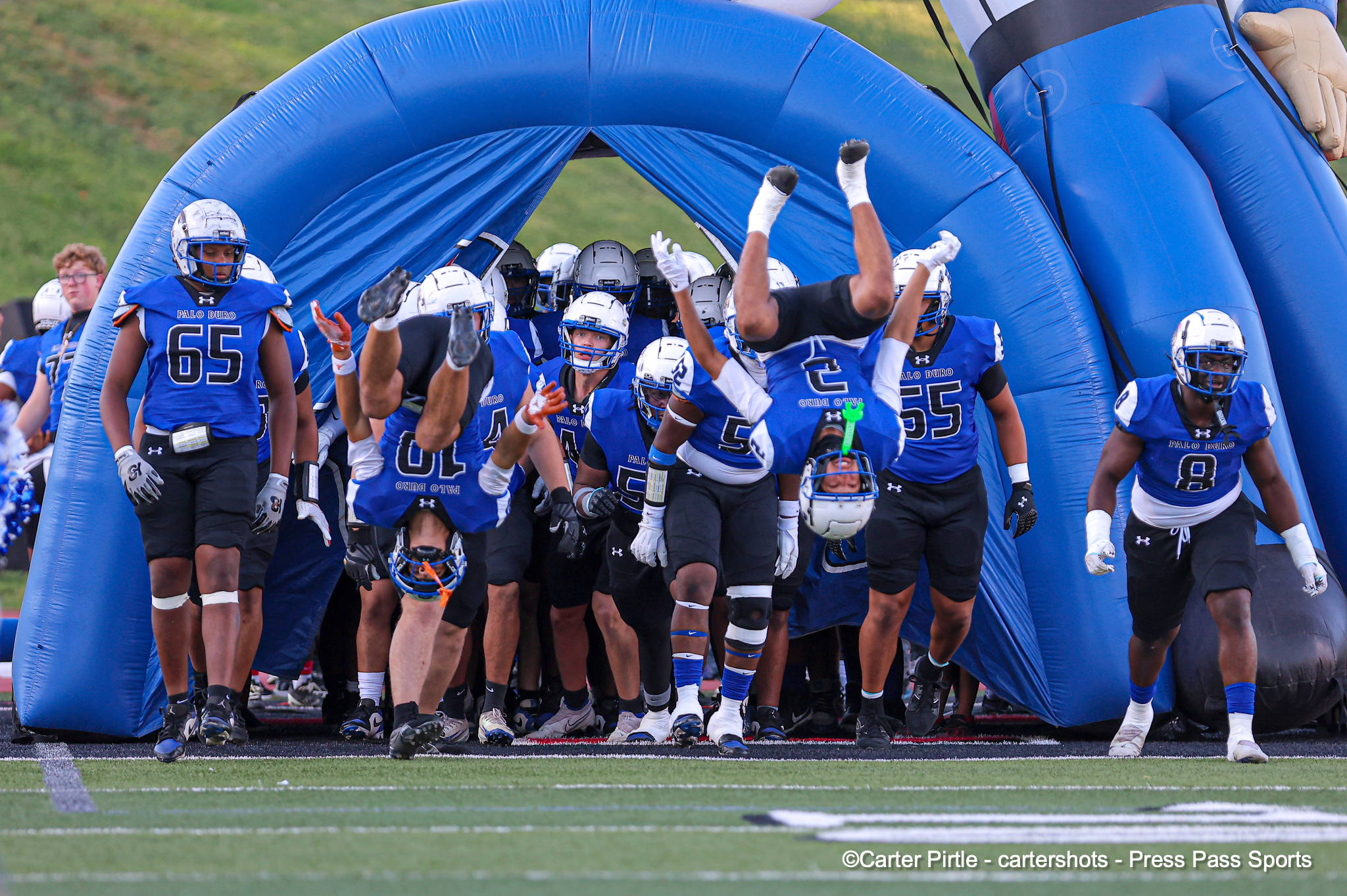 Palo Duro football team bursts onto the field from a large blue inflatable tunnel.