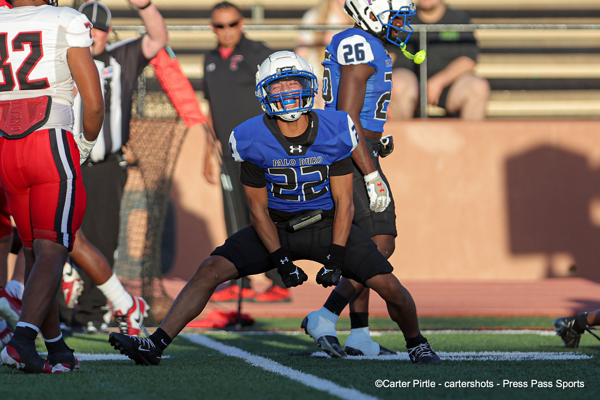 Palo Duro football player in blue jersey #32 runs on the field during a game, with opponents around him.