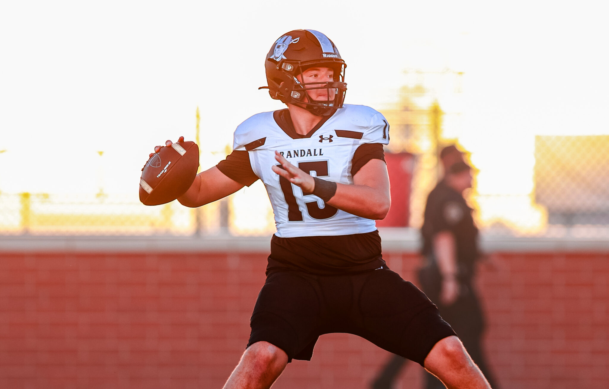 Hendrix Funk 02 | Press Pass Sports Football quarterback in white jersey (#13) holding ball, about to pass on a sunny sideline field.