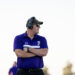 dalhart-vs-panhandle-football-jpegJoe-pps-2 | Press Pass Sports Middle-aged man wearing a purple polo shirt, cap, and sunglasses with over-ear headphones, arms crossed outdoors.