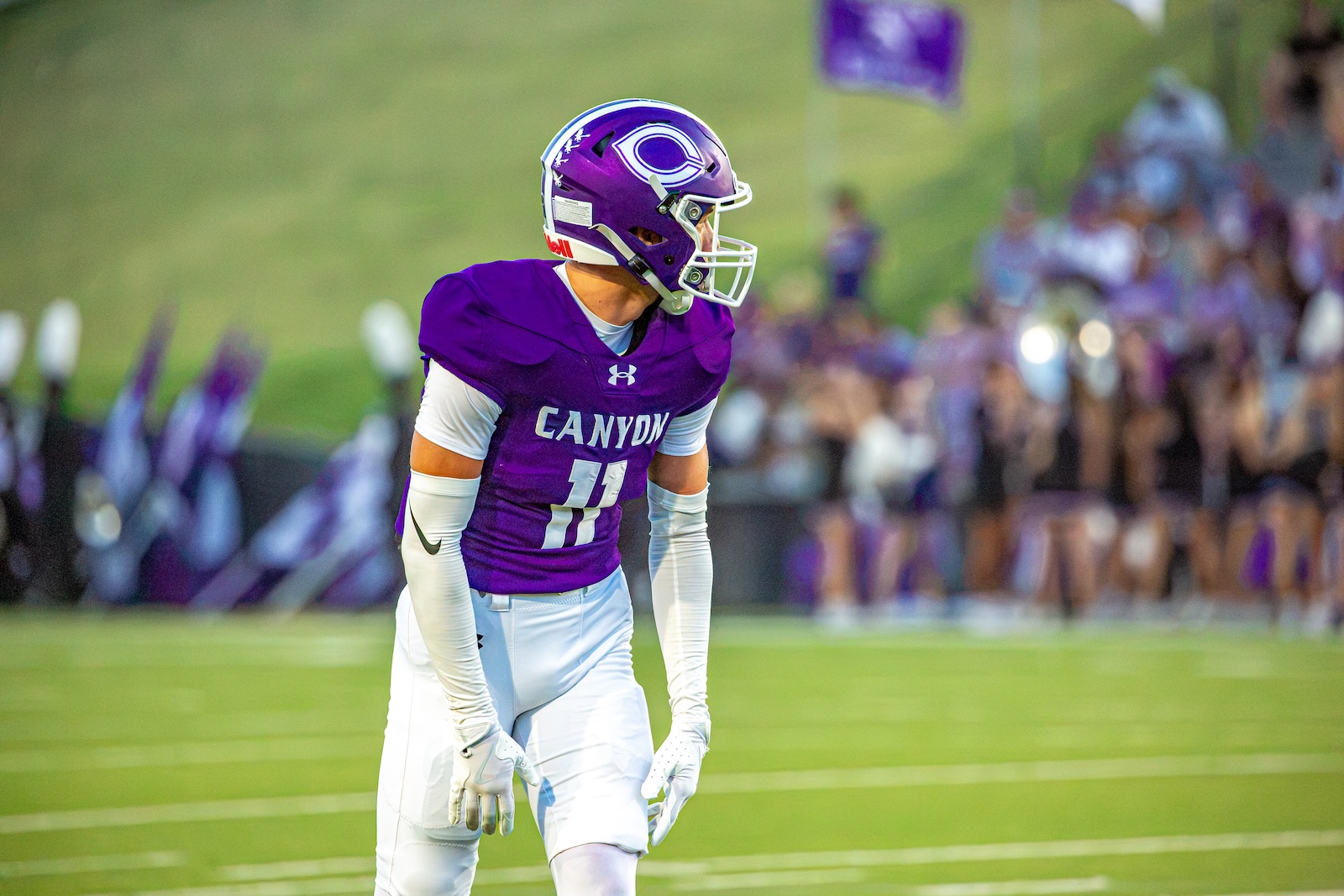 _V4A3016 | Press Pass Sports Canyon football player in a purple jersey number 11 on the field with a blurred crowd in the background.