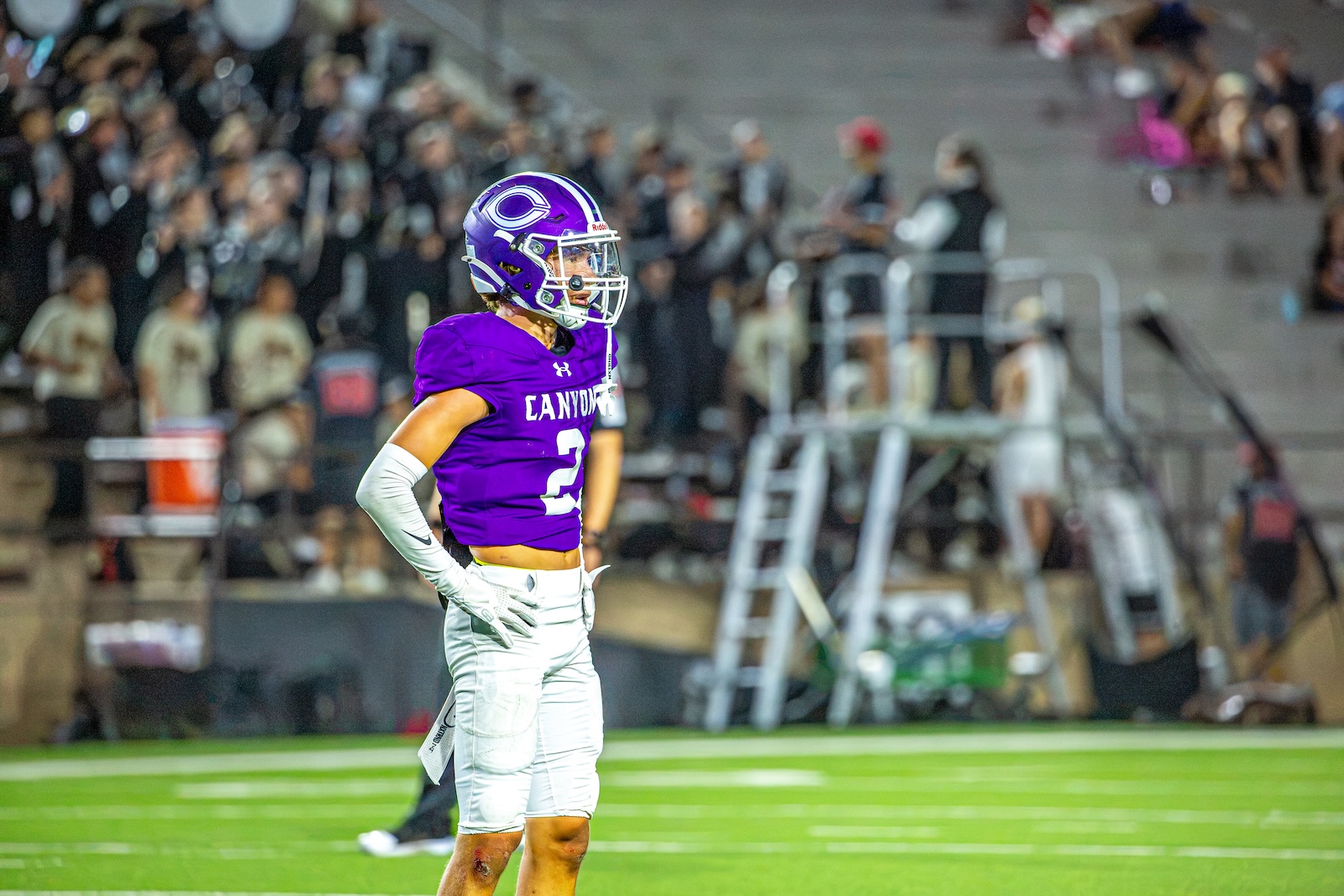 _V4A3145 | Press Pass Sports Football player in a purple Canyon jersey, number 2, stands on the field with hands on hips during a game.