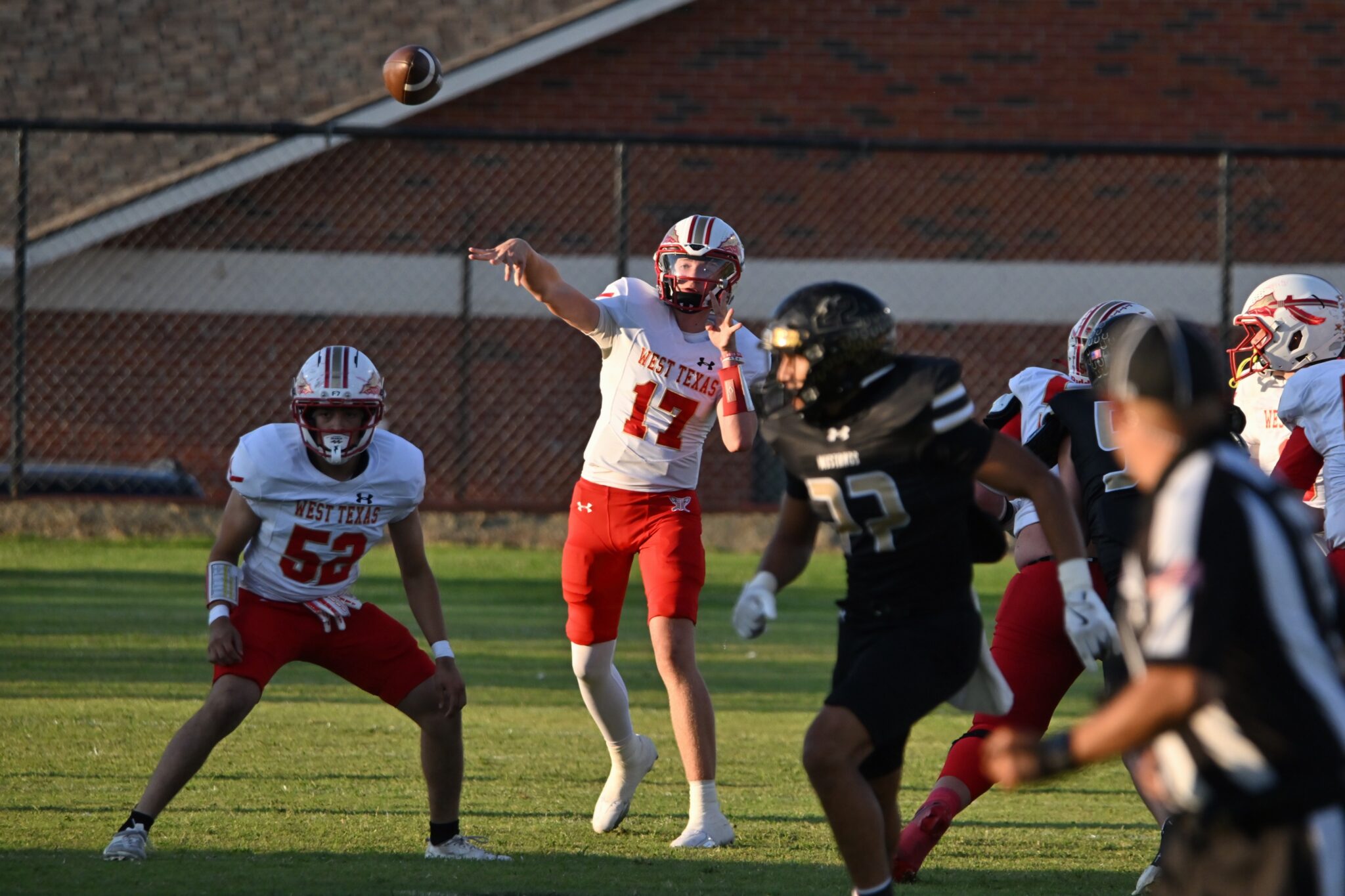 image8 4 | Press Pass Sports Quarterback in white and red West Texas uniform throws a pass as teammates and defenders close in on the field.