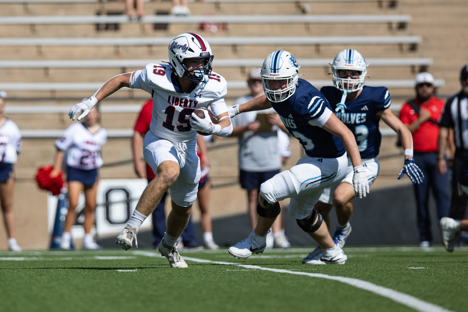 LHS-WPHS-FB-4 | Press Pass Sports Liberty ball carrier in white #19 runs with the ball as a defender in navy pursues on a bright field.
