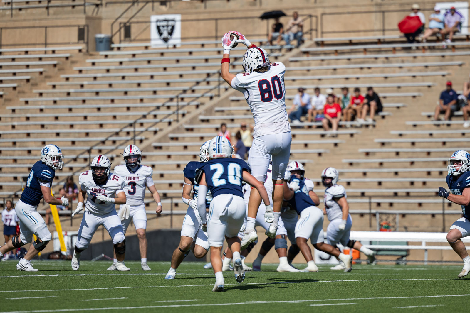 LHS-WPHS-FB-12 | Press Pass Sports Football player in white jersey #80 leaps upward to catch a pass during a game, with defenders and teammates around on a green field.