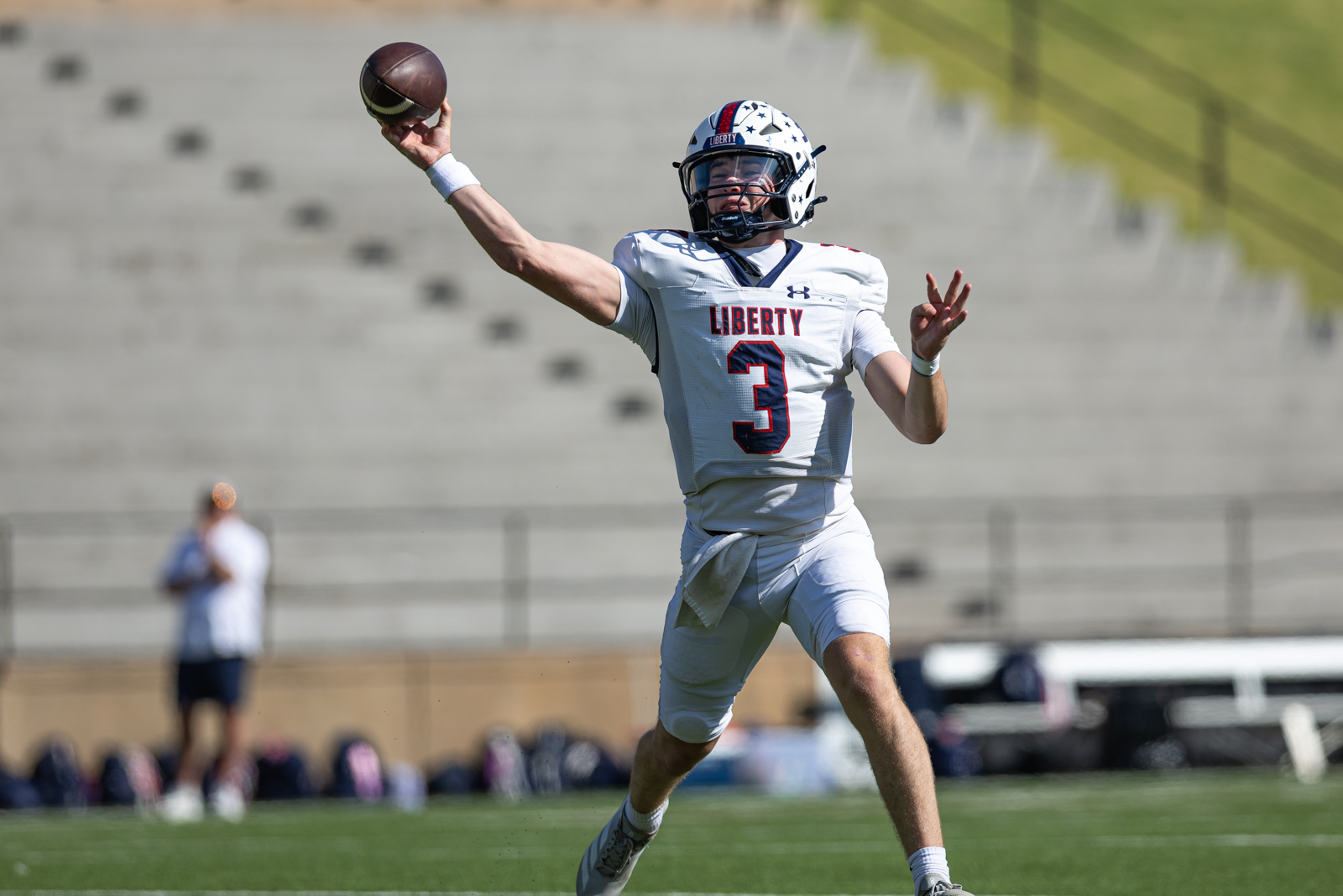 LHS-WPHS-FB-22 | Press Pass Sports Liberty football quarterback in white jersey #3 throwing a pass on a sunny field.