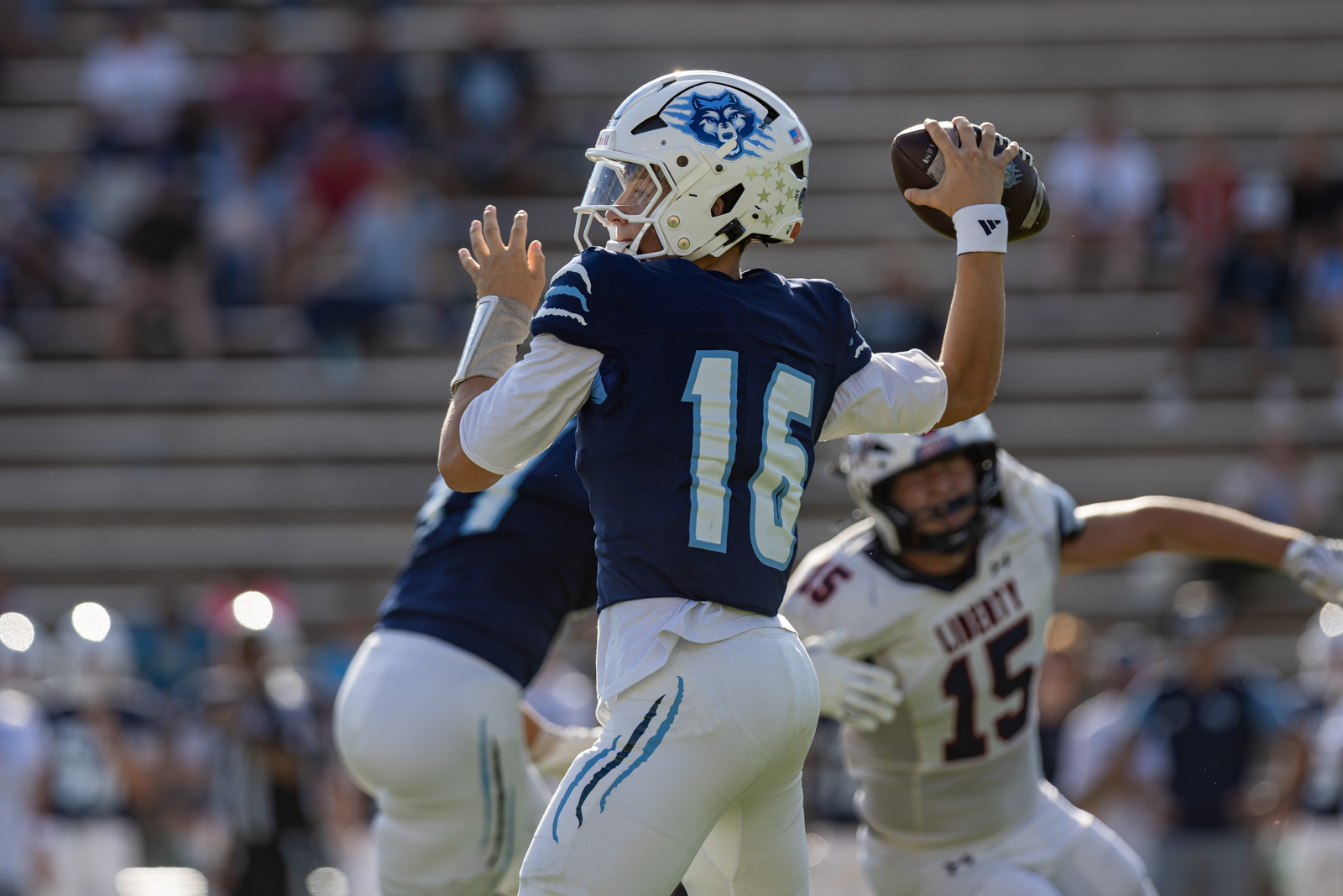 LHS-WPHS-FB-41 | Press Pass Sports Quarterback in blue jersey number 16 throwing a football during a game in a stadium.