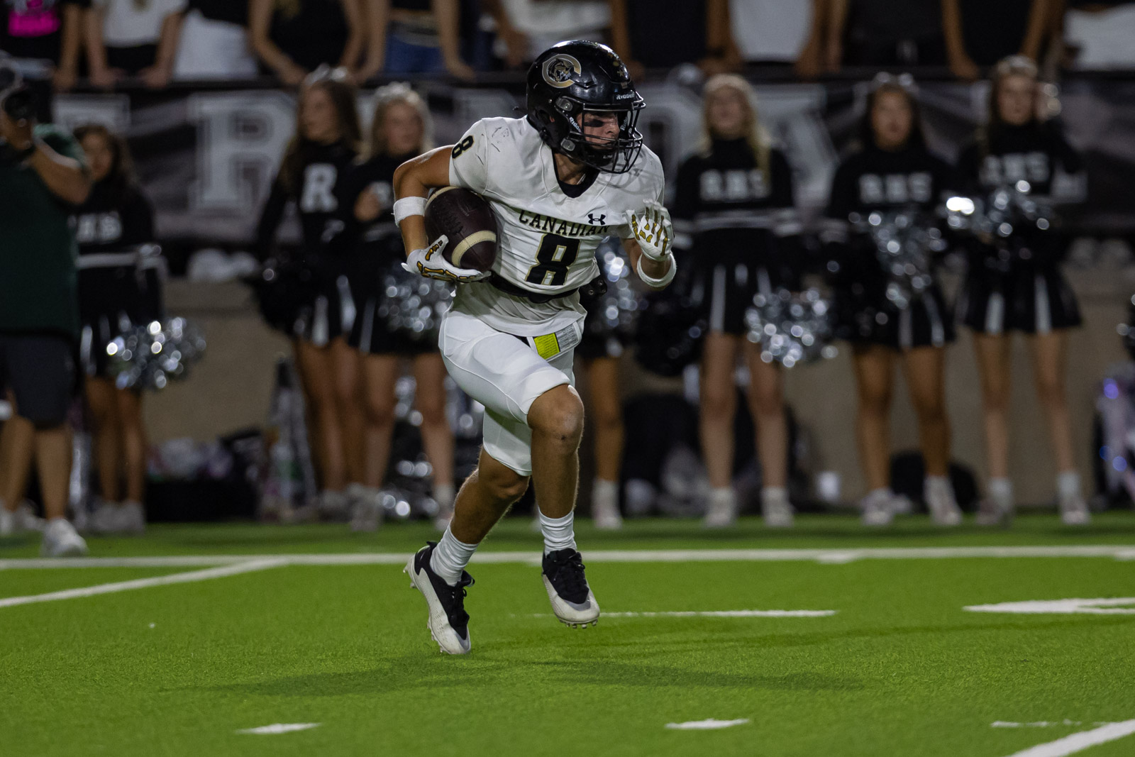 CHS-RHS-FB-31 | Press Pass Sports Football player in white jersey (#8) running with ball on a green turf field, crowd and cheerleaders in the background.