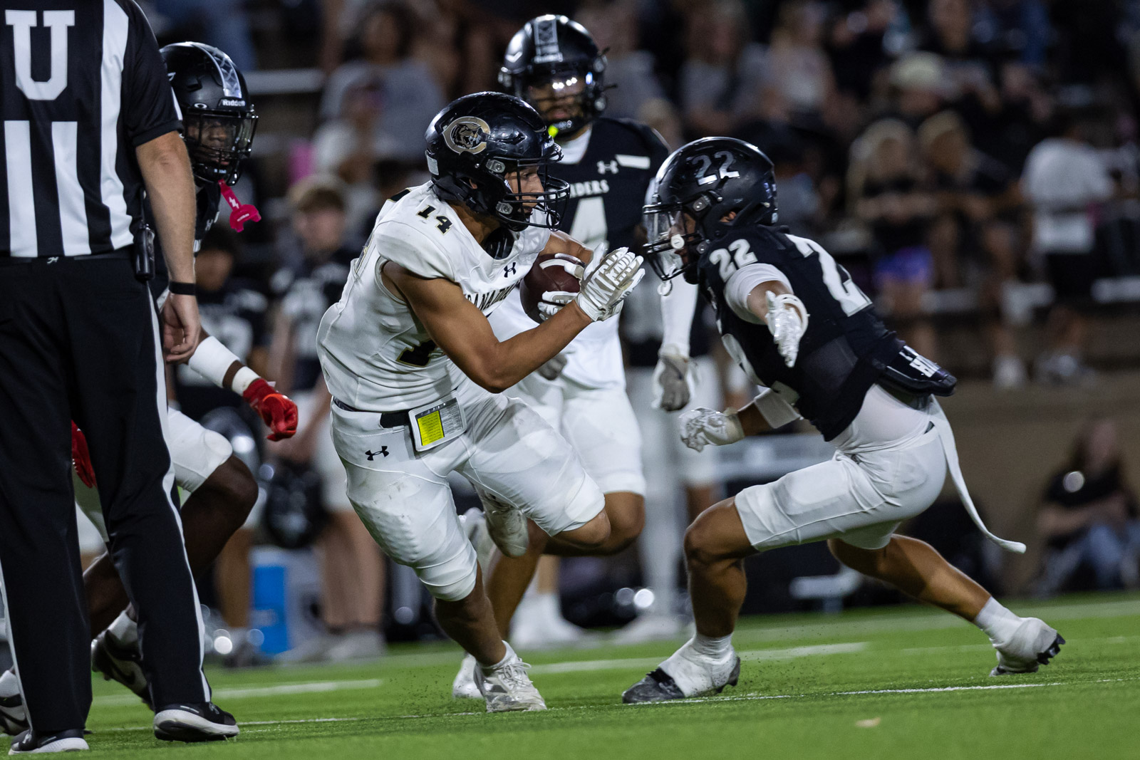CHS-RHS-FB-32 | Press Pass Sports Running back in white jersey with the ball dodges a defender in a black jersey during a football game on a grass field.