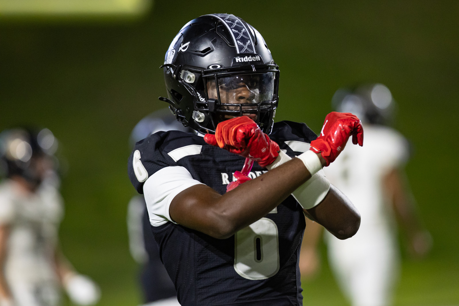 CHS-RHS-FB-51 | Press Pass Sports Football player in black uniform and red gloves crossing arms in celebration on a field