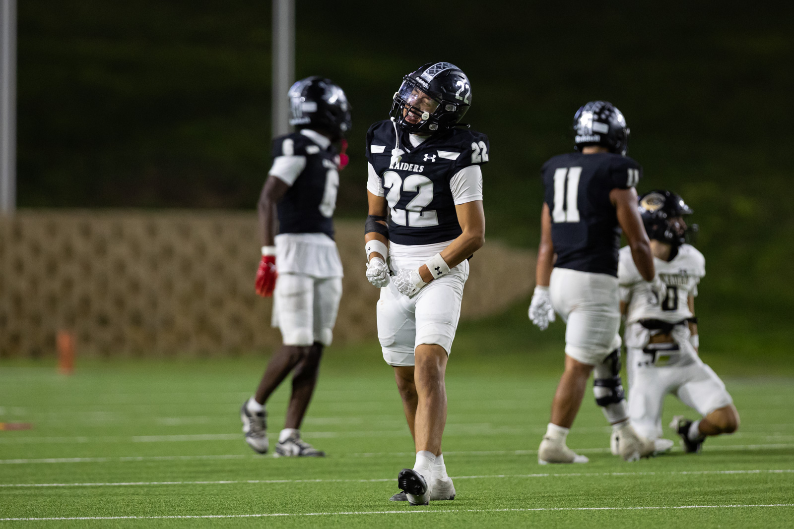 CHS-RHS-FB-53 | Press Pass Sports American football players on a lit night field; central player #22 stands with gloved fists near his waist.