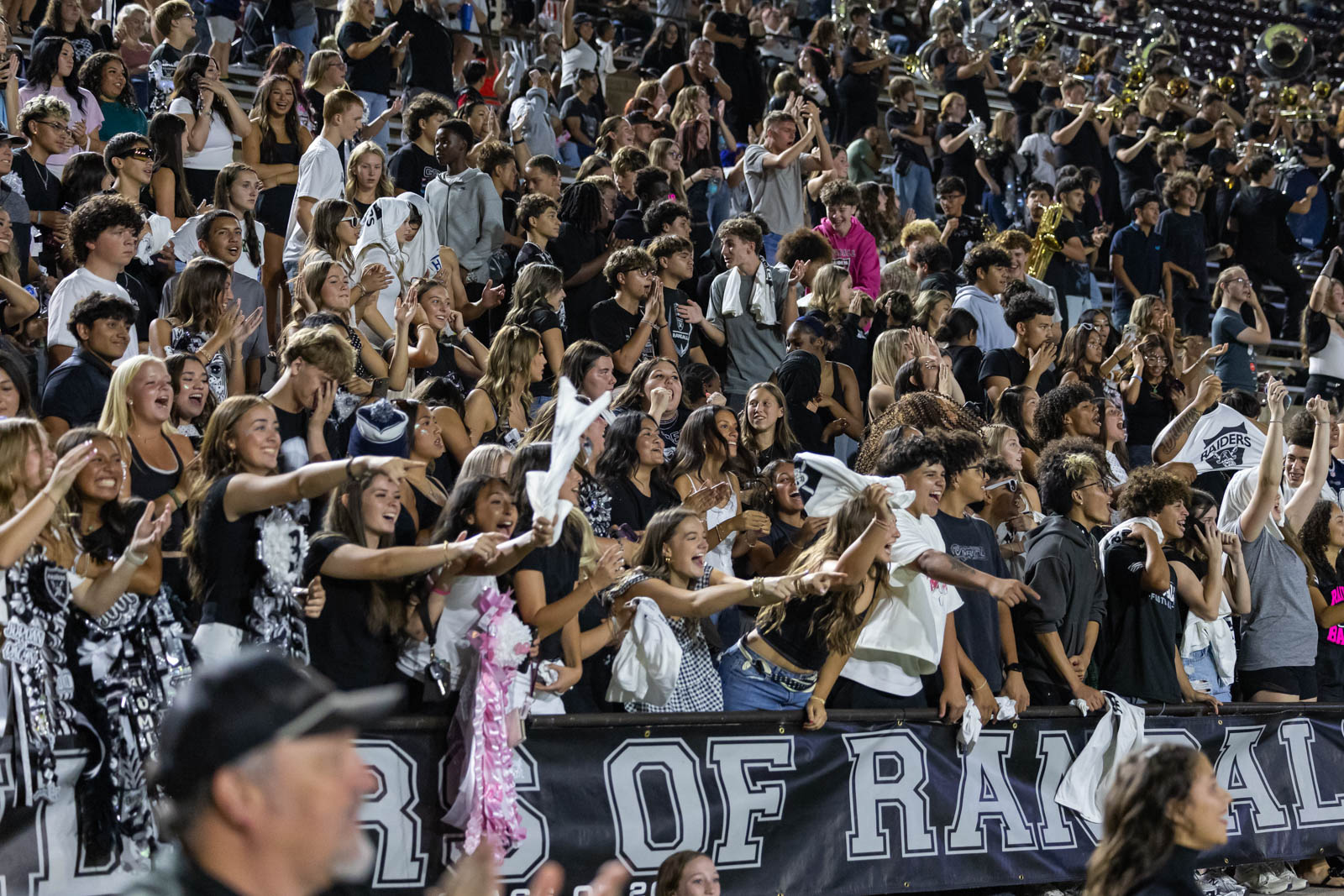 CHS-RHS-FB-59 | Press Pass Sports Large crowd of students in stadium bleachers cheering and waving towels during a game or rally, with a banner in the foreground.