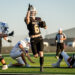 lubbock-christian-vs-bushland-football-jpegJoe-11 | Press Pass Sports Falcons player in black #6 leaps with ball as he runs toward the end zone during a daytime football game; defenders in white nearby and a referee in the background.