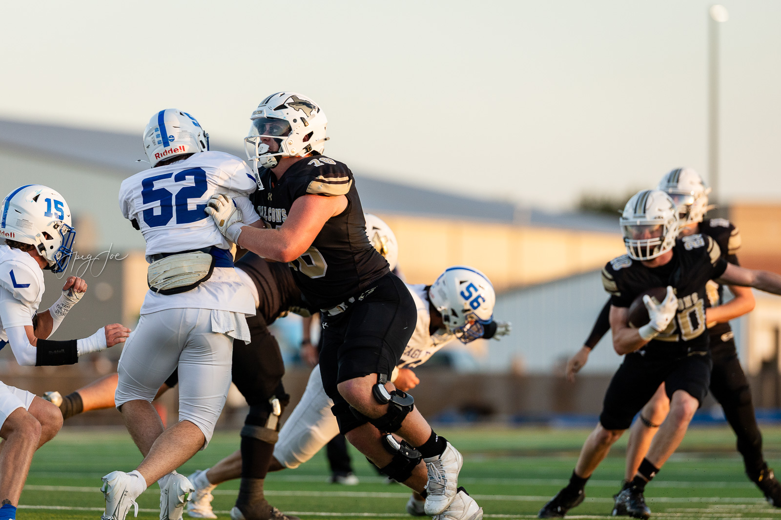lubbock-christian-vs-bushland-football-jpegJoe-16 | Press Pass Sports Football players collide on a sunny field during a high-tensity moment of a game, with white and black uniforms clashing near mid-field.