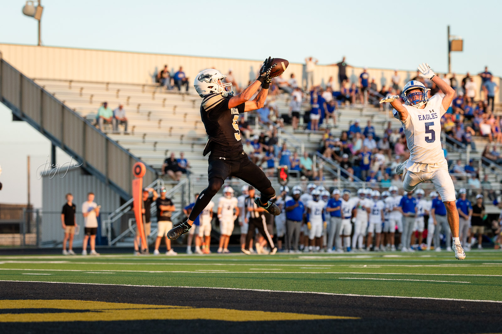 lubbock-christian-vs-bushland-football-jpegJoe-17 | Press Pass Sports Football player in black leaps to catch a pass as a defender in white (number 5) jumps to block in a crowded stadium.