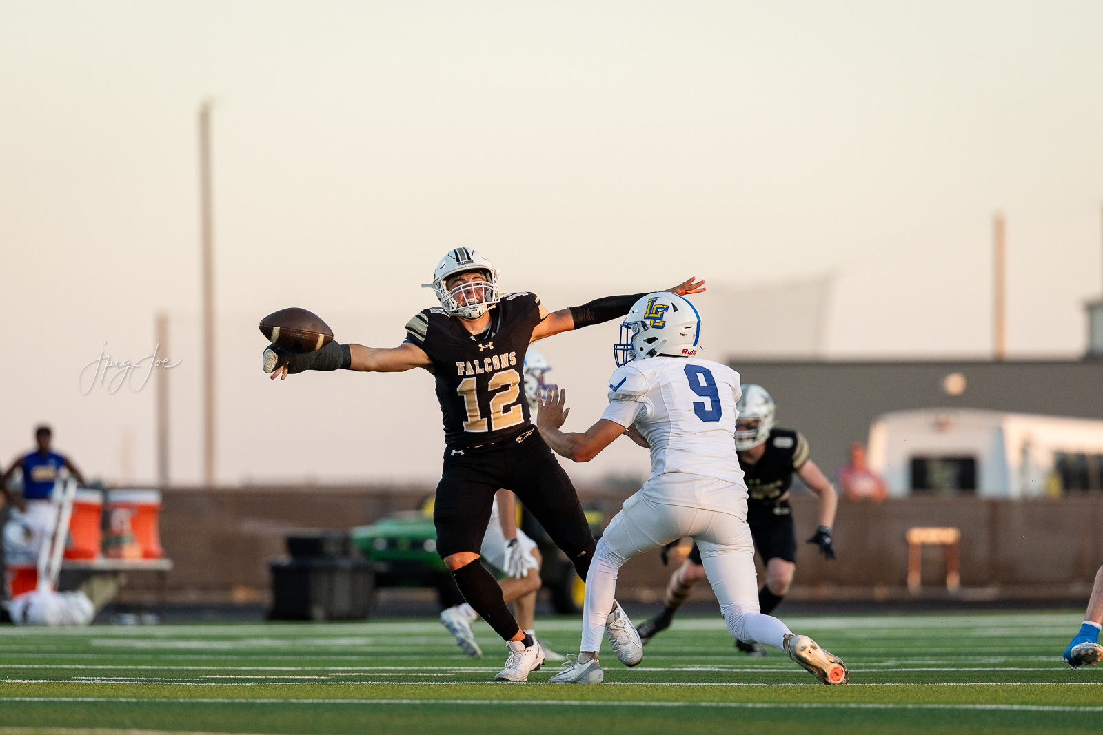 lubbock-christian-vs-bushland-football-jpegJoe-20 | Press Pass Sports Football player in black Falcons jersey #12 attempts a catch while another player in white #9 defends on a sunny sideline field.