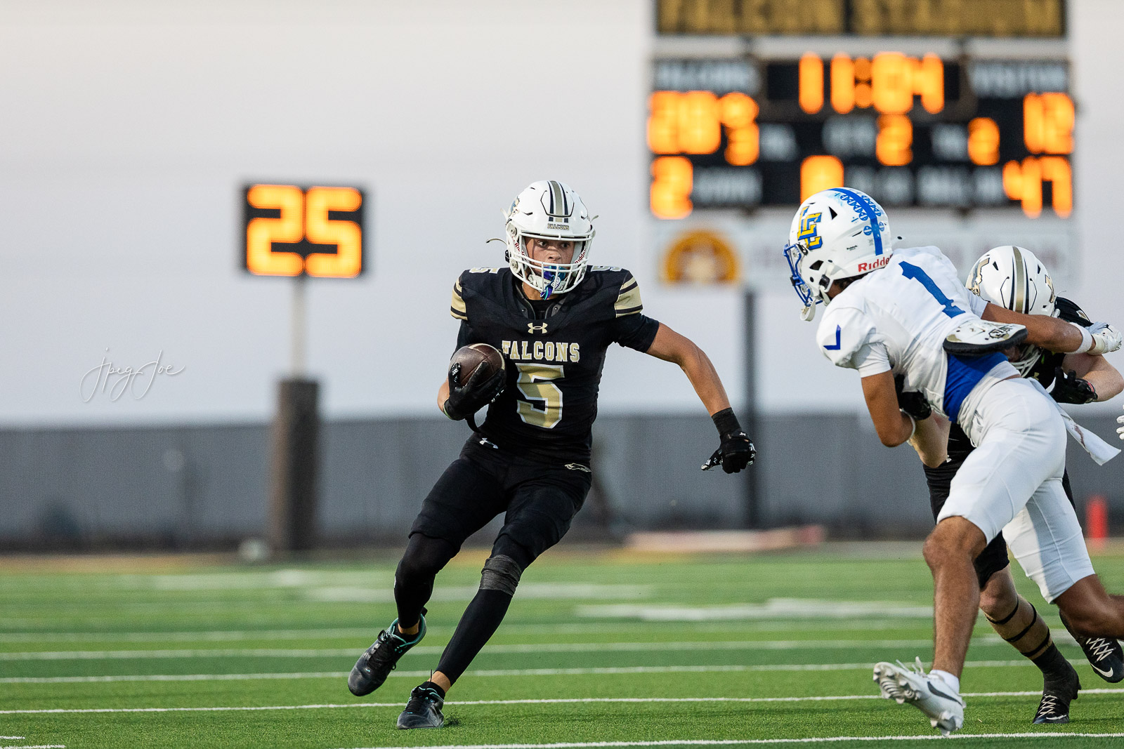 lubbock-christian-vs-bushland-football-jpegJoe-24 | Press Pass Sports High-school football game: Falcons runner carrying the ball, tacklers in white jerseys close behind on a green field with a bright scoreboard in the background.
