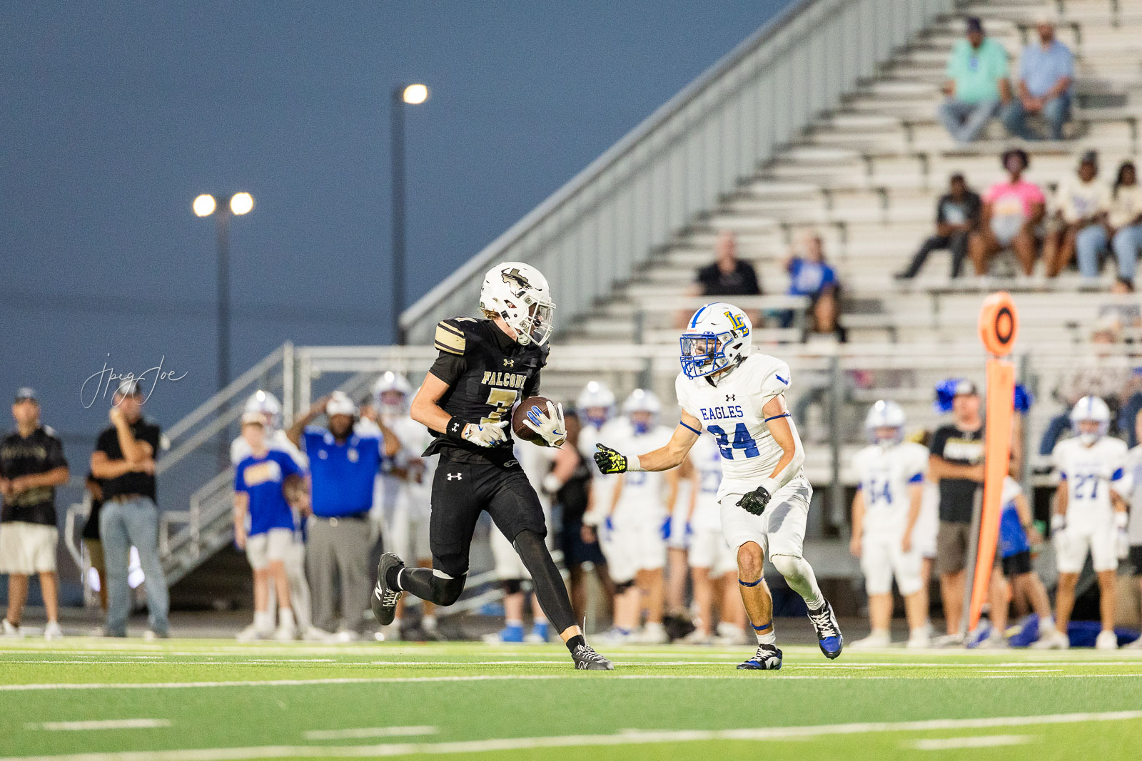 lubbock-christian-vs-bushland-football-jpegJoe-30 | Press Pass Sports Football game action: a Falcons player in black with ball evades a pursuing Eagles defender in white, on a bright turf field at dusk with bleachers in the background.