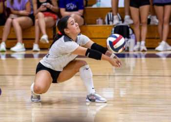 CHS-RHS-VB-5 | Press Pass Sports Volleyball player dives low to dig the ball on a polished gym floor, with spectators in the background.