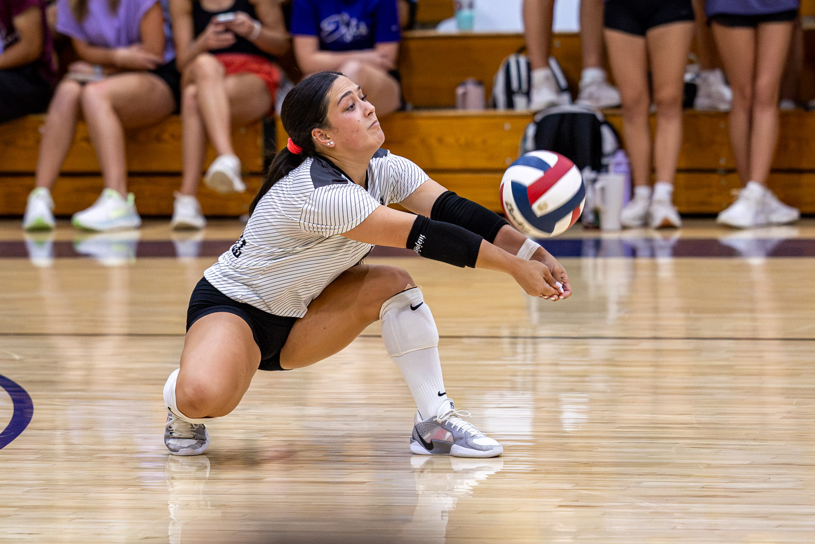CHS-RHS-VB-5 | Press Pass Sports Volleyball player dives low to dig the ball on a polished gym floor, with spectators in the background.