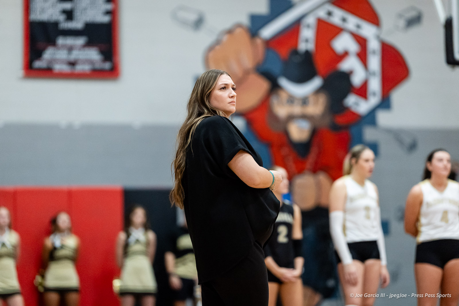 amarillo-high-vs-tascosa-volleyball-jpegJoe-pps-1 | Press Pass Sports Coach in a black shirt watching players during a gym practice, with a large mural in the background.
