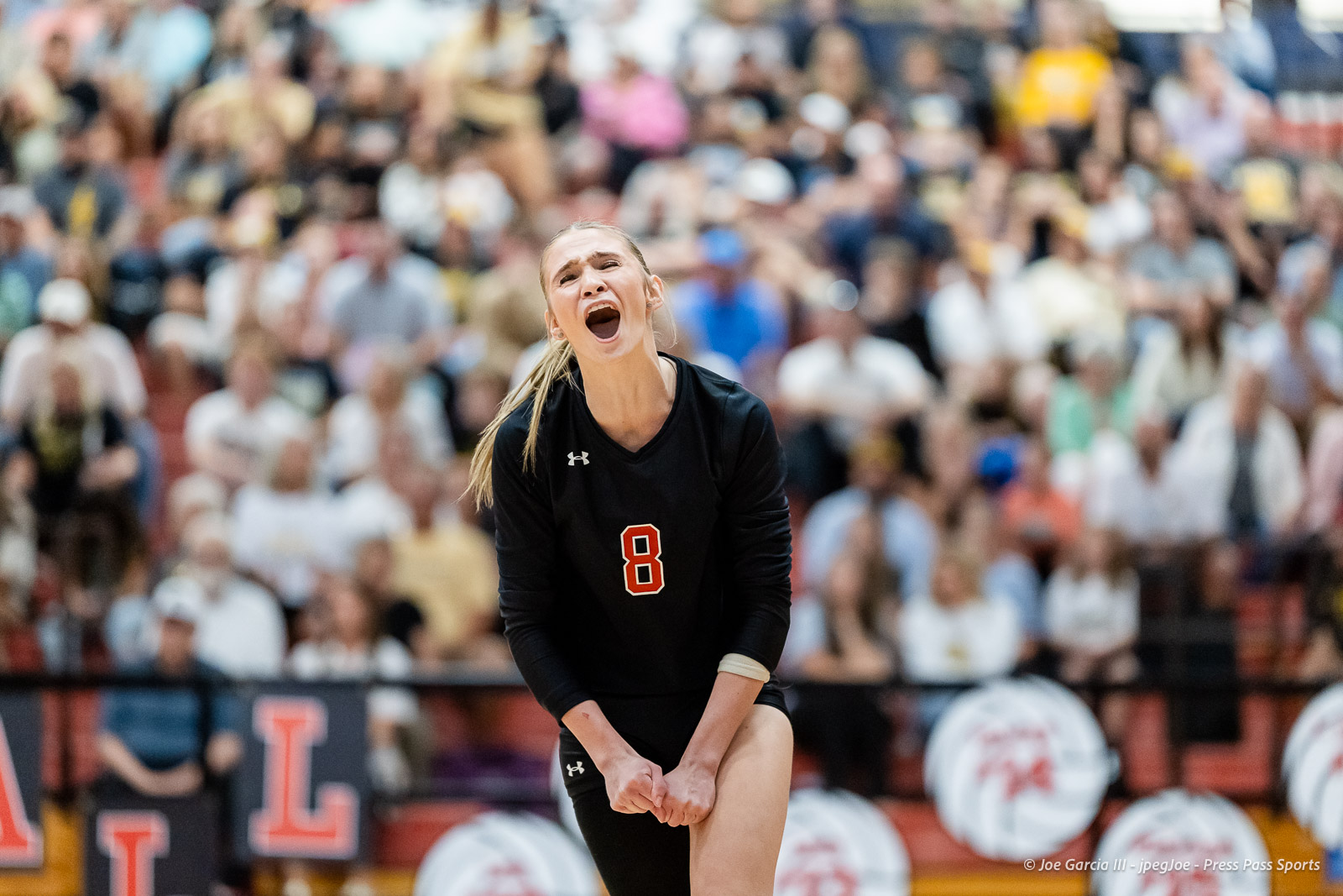 amarillo-high-vs-tascosa-volleyball-jpegJoe-pps-4 | Press Pass Sports Volleyball player wearing black jersey with number 8 screaming in celebration as the crowded gym watches.
