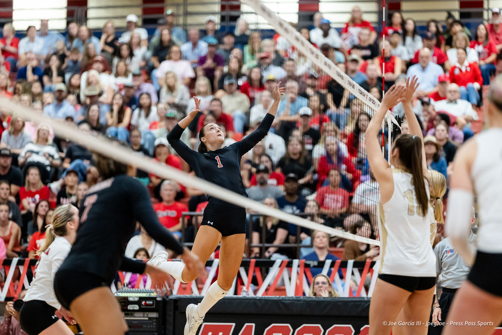 amarillo-high-vs-tascosa-volleyball-jpegJoe-pps-12 | Press Pass Sports Volleyball player in a black uniform (number 1) leaps to spike near the net as a crowded gym watches.